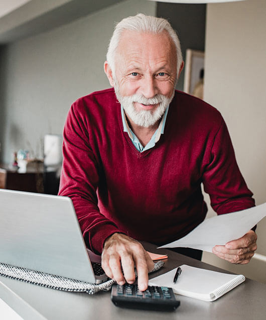 Senior citizen man calculating with his laptop and a paper